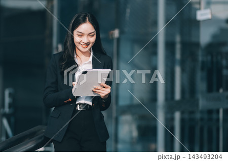 Young businesswoman smiling while working with digital tablet at modern office building 143493204