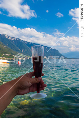 Hand holding a glass of red wine with a scenic panoramic view of Lake Geneva in Montreux, Switzerland Hand holding a glass of red wine with a scenic panoramic view of Lake Geneva in Montreux, Switzerland 143493614
