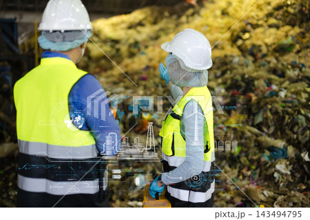 Engineers analyze smart waste management and green energy data overlays at a recycling facility. Engineers analyze smart waste management and green energy data overlays at a recycling facility. 143494795