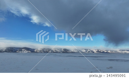 凍ったバイカル湖と雪山の上の劇的な雲 143495091