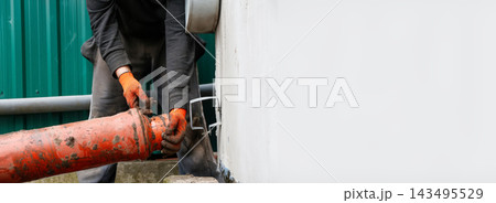 Worker in orange gloves connecting an orange plastic sewer pipe outdoors. Plumbing, construction, and utility maintenance concept. Banner with copy space Worker in orange gloves connecting an orange plastic sewer pipe outdoors. Plumbing, construction, and utility maintenance concept. Banner with copy space 143495529