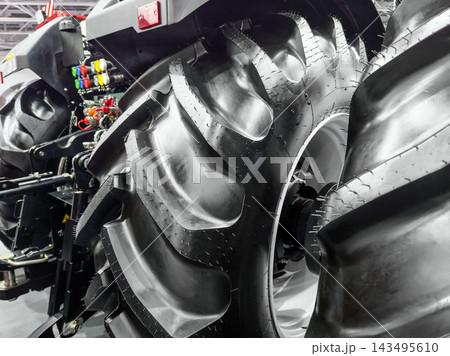 Tractor tire details showcased at an agricultural equipment exhibition in a large indoor venue 143495610