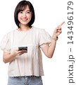 Happy Asian woman holding smartphone pointing finger up side display copy space isolated transparency background studio shot showing happy expression presentation 143496179