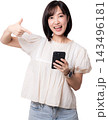 Happy asian woman pointing index finger at smartphone promoting artificial intelligence application with excited facial expression against plain transparency background studio shot 143496181