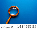 Vintage wooden magnifying glass with brass ring on vibrant blue background 143496383