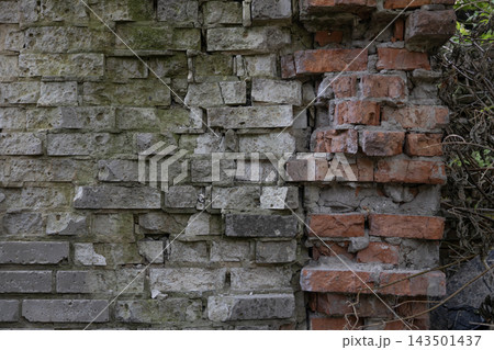 Ruined old brick wall texture with moss, grey blocks and damaged red clay masonry. Vintage abandoned industrial background for architectural design, grunge urban patterns and historical decay. Ruined old brick wall texture with moss, grey blocks and damaged red clay masonry. Vintage abandoned industrial background for architectural design, grunge urban patterns and historical decay. 143501437