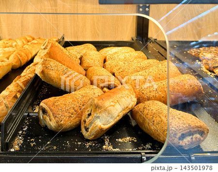 Fresh savory pastries displayed in a modern bakery showcase cabinet, inviting customers to purchase delicious golden flaky baked goods ready for breakfast or a quick afternoon snack 143501978