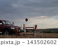 Man stands near brown SUV on open field. 143502602