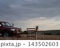 Vehicle parked near a table and chairs in an field. 143502603