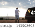 Man takes photographs in a field during sunset. 143502608