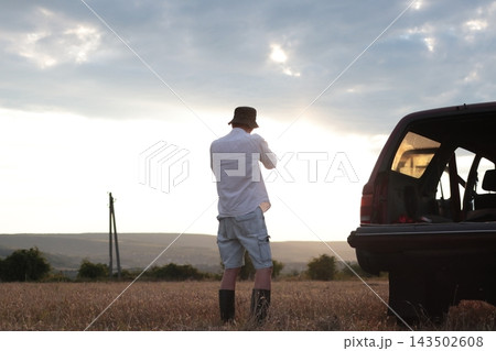 Man takes photographs in a field during sunset. 143502608