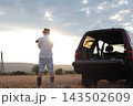 Man takes photographs in a field during sunset. 143502609