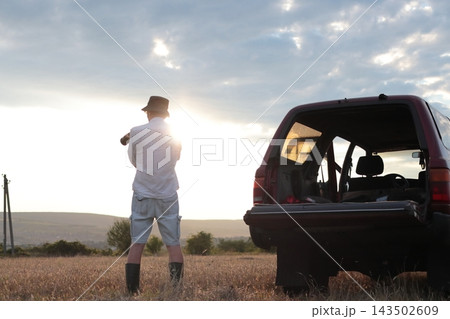 Man takes photographs in a field during sunset. 143502609