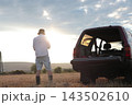 Man takes photographs in a field during sunset. 143502610