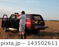 Man takes photographs in a field during sunset. 143502611