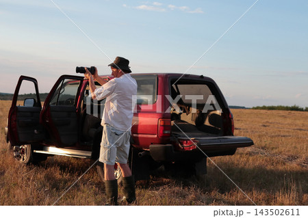 Man takes photographs in a field during sunset. 143502611