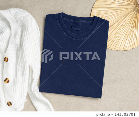 Washed navy blue folded t-shirt mockup near cardigan and palm leaf, template for print on demand 143502701