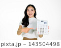 Young Asian Woman Smiling and Pointing at a Large Calculator on White Background Young Asian Woman Smiling and Pointing at a Large Calculator on White Background 143504498