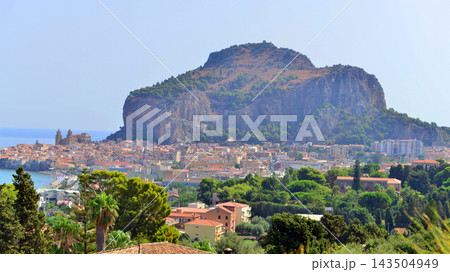 Cefalu, Italy. 22 August 2026. A panoramic view of the old town, situated right by the sea and featuring beautiful architecture. The La Rocca rock towers over the town. 143504949