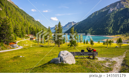 Visitors enjoy the view of Lake Neves in South Tyrol, located at the end of the Molini Valley in the Zillertal Alps, Italy. The area is surrounded by green trees and mountains. Visitors enjoy the view of Lake Neves in South Tyrol, located at the end of the Molini Valley in the Zillertal Alps, Italy. The area is surrounded by green trees and mountains. 143505179