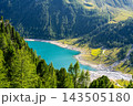 Lake Neves is in South Tyrol at the end of the Molini Valley in the Zillertal Alps. This view shows the clear water and surrounding green trees on a sunny day. 143505180