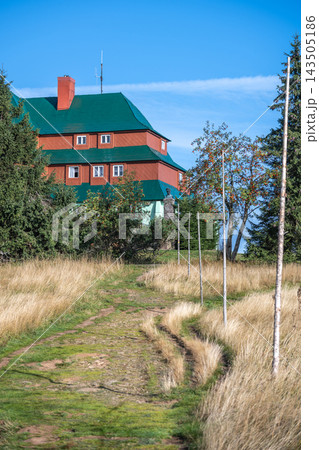 Masaryk's cottage stands on Serlich in the Orlicke Mountains. The path leads up to the cottage surrounded by grass and trees. Clear blue skies can be seen above. Masaryk's cottage stands on Serlich in the Orlicke Mountains. The path leads up to the cottage surrounded by grass and trees. Clear blue skies can be seen above. 143505186