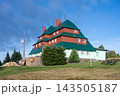 This is Masaryk's cottage located on Serlich. It is a well-known mountain cottage in the Orlicke ountains. The structure features multiple roofs and is surrounded by grass and trees. 143505187