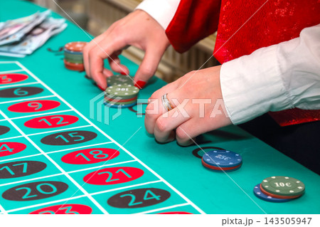 Placing bets at a roulette table with colorful chips in a casino setting 143505947