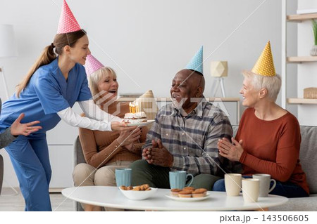Joyful Emotion Displayed By Happy Group Of Four Seniors Including Two Women And Two Men Celebrating A Birthday With Cake And Candles At Home, Enjoying Each Other's Company In A Cheerful Atmosphere. Joyful Emotion Displayed By Happy Group Of Four Seniors Including Two Women And Two Men Celebrating A Birthday With Cake And Candles At Home, Enjoying Each Other's Company In A Cheerful Atmosphere. 143506605