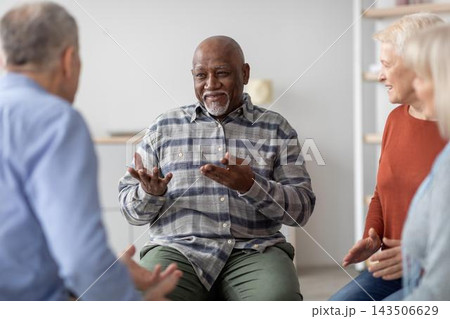 Focused African American Man Engaging In Discussion With Three Friends In Workshop Setting. Group Collaboration At Office Environment, Sharing Ideas And Solutions. Business Concept. Focused African American Man Engaging In Discussion With Three Friends In Workshop Setting. Group Collaboration At Office Environment, Sharing Ideas And Solutions. Business Concept. 143506629