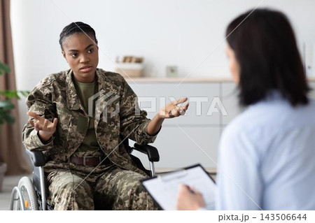Worried African American Woman In Wheelchair Engaging In Conversation With Therapist At Office, Discussing Emotional Wellbeing And Therapy Session. Worried African American Woman In Wheelchair Engaging In Conversation With Therapist At Office, Discussing Emotional Wellbeing And Therapy Session. 143506644