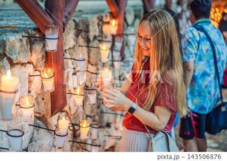 Woman holding a glowing candle during a quiet festive moment. 143506876