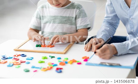 Focused Caucasian Child And Adult Playing With Colorful Letters, Engaging In Educational Activity Together At Office Desk. Exploring Language And Learning Through Hands-on Play. Educational Concept. Focused Caucasian Child And Adult Playing With Colorful Letters, Engaging In Educational Activity Together At Office Desk. Exploring Language And Learning Through Hands-on Play. Educational Concept. 143506878
