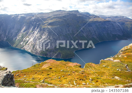View of a fjord in Norway surrounded by cliffs and hills during a clear day View of a fjord in Norway surrounded by cliffs and hills during a clear day 143507186