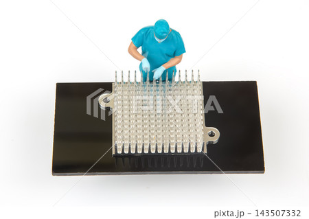 Miniature people working on a computer chip at a lab setting 143507332