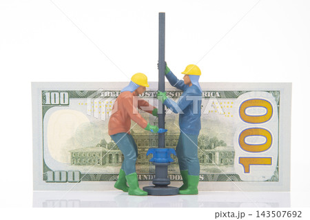 Miniature figures work on a construction site using a drill above a hundred dollar bill Miniature figures work on a construction site using a drill above a hundred dollar bill 143507692