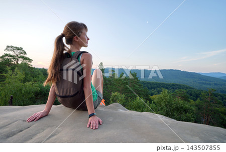 Lonely woman hiker sitting alone on rocky mountain top enjoying view of morning nature on wilderness trail. Active lifestyle concept Lonely woman hiker sitting alone on rocky mountain top enjoying view of morning nature on wilderness trail. Active lifestyle concept 143507855