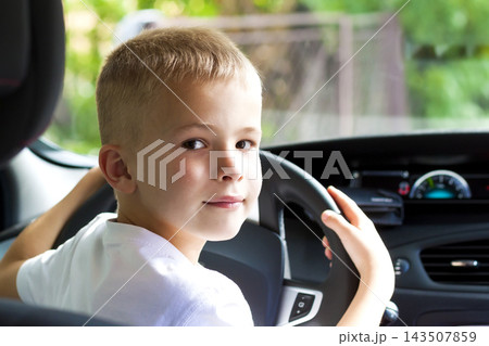 Little child boy behind the steering wheel of a car Little child boy behind the steering wheel of a car 143507859