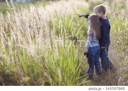 Little boy and little girl standing holding hands looking on horizont. Rear view. Little boy and little girl standing holding hands looking on horizont. Rear view. 143507860