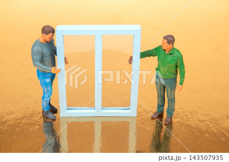 Miniature figures hold and display a blue window frame on a reflective surface Miniature figures hold and display a blue window frame on a reflective surface 143507935