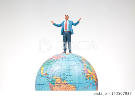 Miniature figures standing globe creating a sense of adventure and exploration in a simple setting Miniature figures standing globe creating a sense of adventure and exploration in a simple setting 143507937