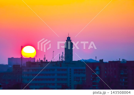 Sunset behind buildings and a tower in a city with a colorful sky 143508004