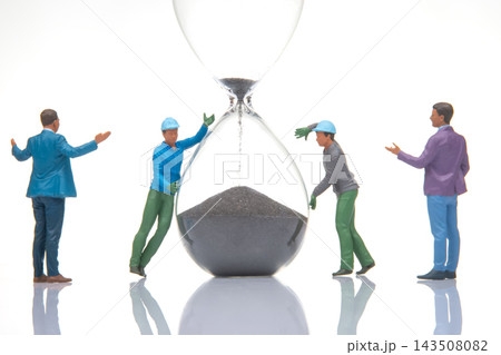 Miniature people working together to move sand in an hourglass 143508082