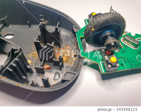 Old computer mouse opened for repair showing components and dirt inside Old computer mouse opened for repair showing components and dirt inside 143508125