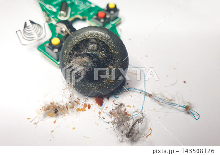 Dust and debris collected around a broken electronic device on a white surface Dust and debris collected around a broken electronic device on a white surface 143508126