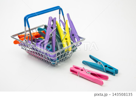 Colorful clothespins in a metal basket on a plain background Colorful clothespins in a metal basket on a plain background 143508135