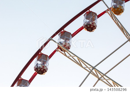 Ferris wheel cabins viewed against a clear sky during the afternoon at a local fairground Ferris wheel cabins viewed against a clear sky during the afternoon at a local fairground 143508296