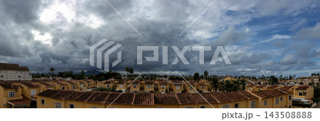 Panoramic view of dramatic storm clouds over Mediterranean townhouses and terracotta rooftops 143508888