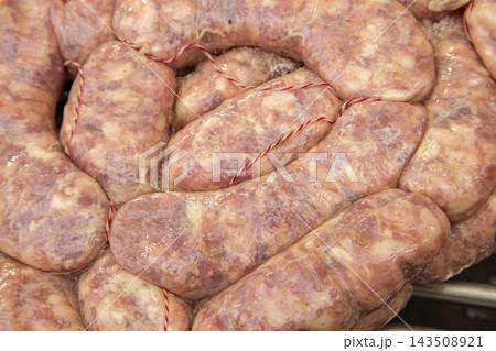 Fresh raw pork sausages tied with butcher twine coiled on barbecue grill Fresh raw pork sausages tied with butcher twine coiled on barbecue grill 143508921