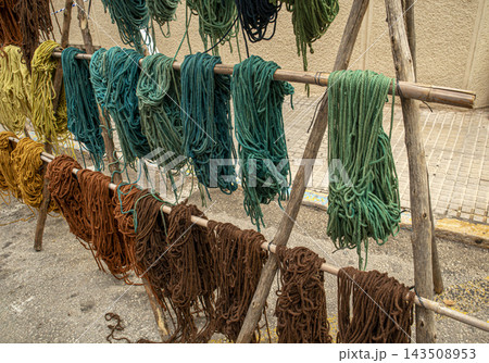 Bundles of Colorful Dyed Wool Yarn Drying on Wooden Racks Outdoors Bundles of Colorful Dyed Wool Yarn Drying on Wooden Racks Outdoors 143508953